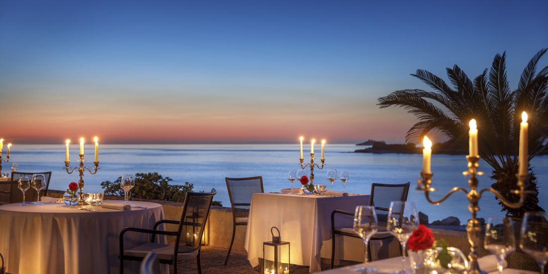 Candlelit dinner setting by the sea at dusk